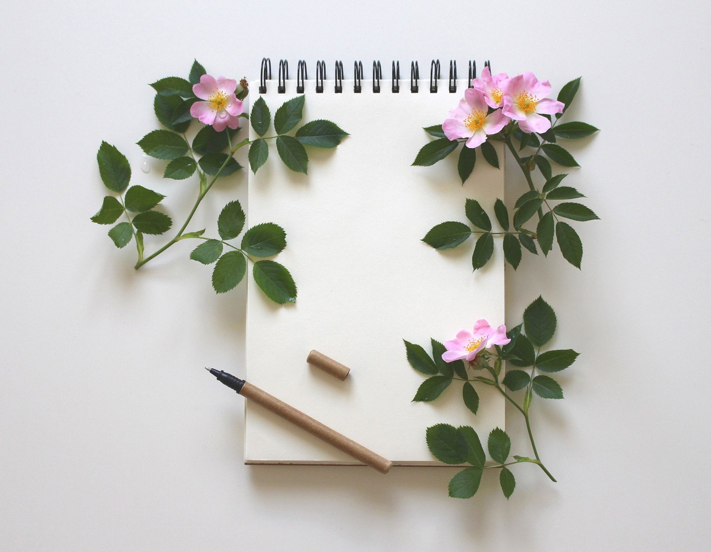 notepad and pen with flowers decorating the corners